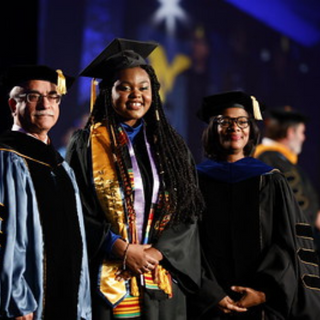 Jazlynne Cathey in academic regalia at a graduation ceremony.
