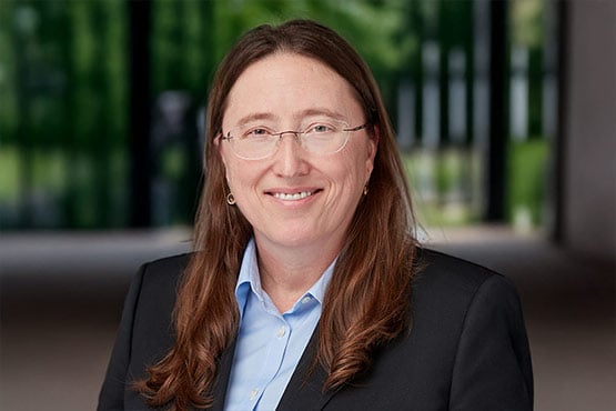 Provost and Vice Chancellor for Academic Affairs- Abby Parrill-Baker
A person with long hair wearing a black suit and light blue shirt, standing in a blurred outdoor setting.