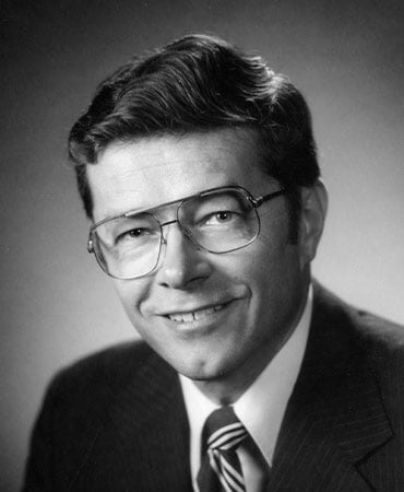 Black and white portrait of Conny Nelson wearing a suit and striped tie with neatly combed hair.